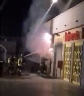 I vigili del fuoco abbattono la serranda del supermercato per fronteggiare il muro di fiamme 